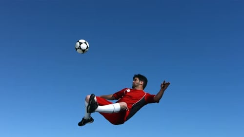 Man in red kicks soccer ball in air