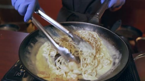 Chef Preparing Pasta With Tongs in a Pan