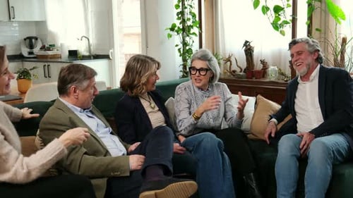 Group of Mature Friends Talking and Laughing on a Sofa at Home