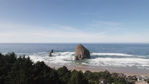 Hills of pine trees give way to Haystack Rock at Cannon Beach