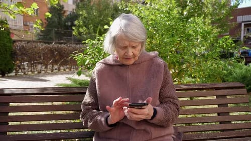 Older Woman Using Smartphone on Park Bench