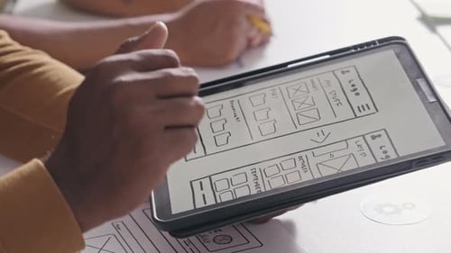 Diseñadores de UX discuten maqueta de interfaz de aplicación móvil en tableta