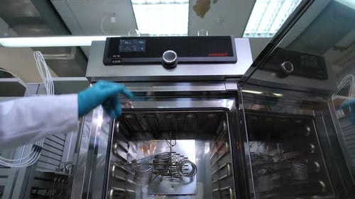 Mitarbeiter schließt Tür zu Werkzeugmaschine und führt Tests im Labor durch