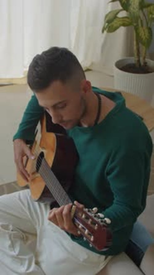 Man Playing Acoustic Guitar Sitting at Home