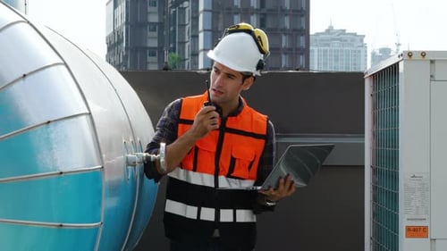 Männlicher technischer Vorarbeiter inspiziert die Wartung, arbeitet am Laptop und befiehlt, während er im Funkruf spricht