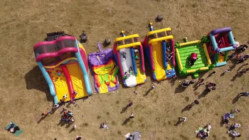 Bird's eye view over many multicolored inflatable outdoor games and bouncy castles for children .