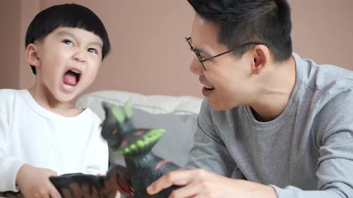 Boy and Adult Playing Dinosaurs Together Indoors