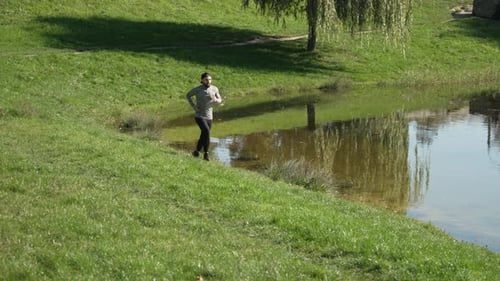 A Man Goes for a Morning Run Near the River in Nature