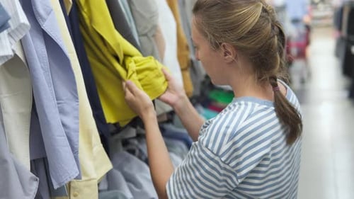 Woman is choosing shirts at a mass market store
