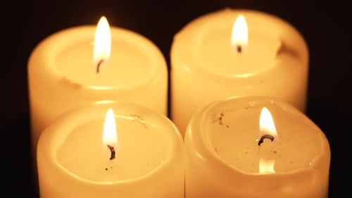 Burning Four Candles Wick Flame Close Up Rotating on Dark Background