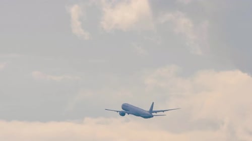 Airplane Ascends into Cloudy Blue Sky