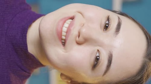 Vertical Video of Asian woman looking at camera smiling.