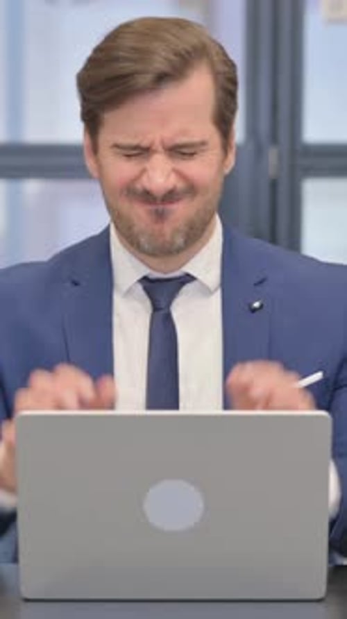 Man Working on Laptop Experiencing Headache in Office