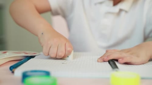 Child Erasing Pencil Marks From Notebook