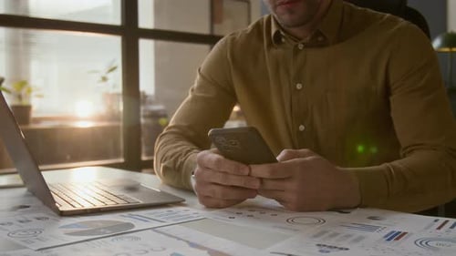 Midsection of Entrepreneur Sending Email to Business Partner Holding Smartphone