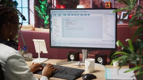 Woman in Home Office Looking at UI on PC Screen Typing Code