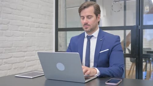 Man in Suit Typing, Rubs Sore Neck