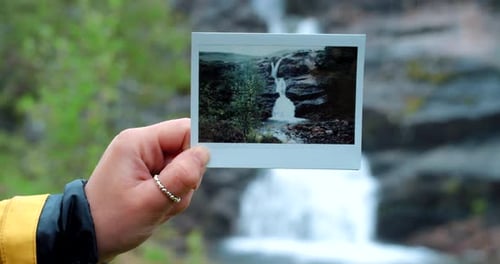 Hand Holding Polaroid of Waterfall in Nature
