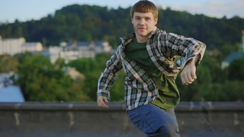 Kaukasischer lächelnder Tänzer, der draußen auf dem Dach Hip Hop spielt Brunette Mann genießt Tanzunterricht
