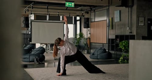 Caucasian Female Office Worker Performs Yoga and Stretching on a Grey Carpet in a Modern Office