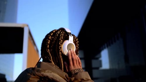 Young Woman Listens to Music in the City