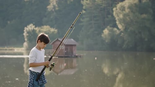 Boy Prepares Fishing Rod Spining Reel and Tightening Line