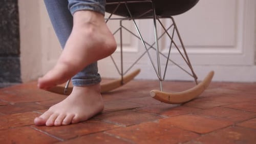 A Woman's Feet Gently Swaying the Rocking Chair - Close Up