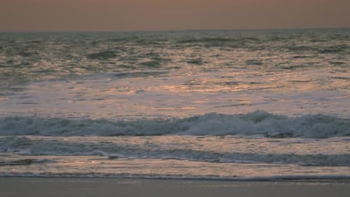 Slow Motion Ocean Footage with Orange Sunrise Lighting Reflecting on Surface