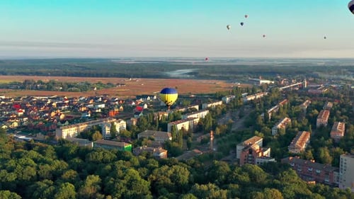 Multicolored balloons fly over trees. Nice top view of the park, forest covered with greenery.