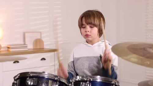 Little boy with drumsticks learning how to play drums indoors