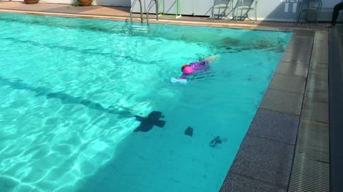 Asian small child girl practices swimming in the pool, outdoor swimming pool.