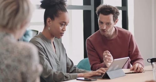 Collègues en réunion regardant une tablette numérique