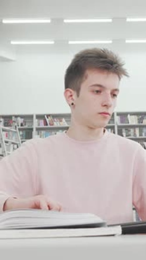 Estudiante masculino concentrado inmerso en el trabajo con una computadora portátil en una biblioteca moderna