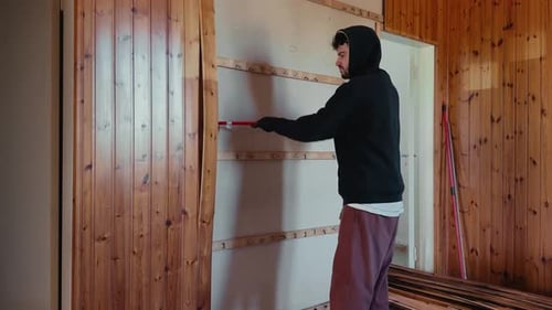 Man removing wooden wall panels with crowbar during home renovation demolition work