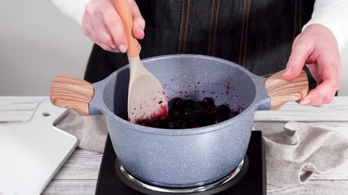 Person Stirring Berries in a Cooking Pot
