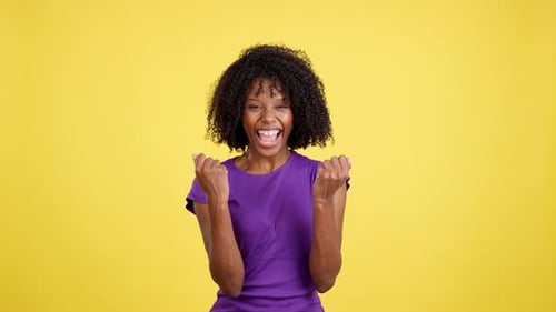Happy Woman with Afro Hair Celebrating While Raising Fists