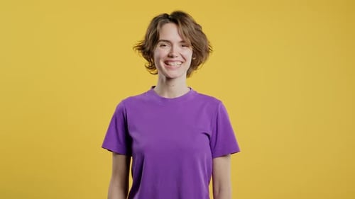 Woman Smiling in Purple Shirt Against Yellow Background
