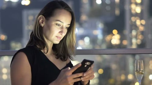 Young, Elegant Beautiful Woman Texting On Smartphone In Luxury Bar At Night