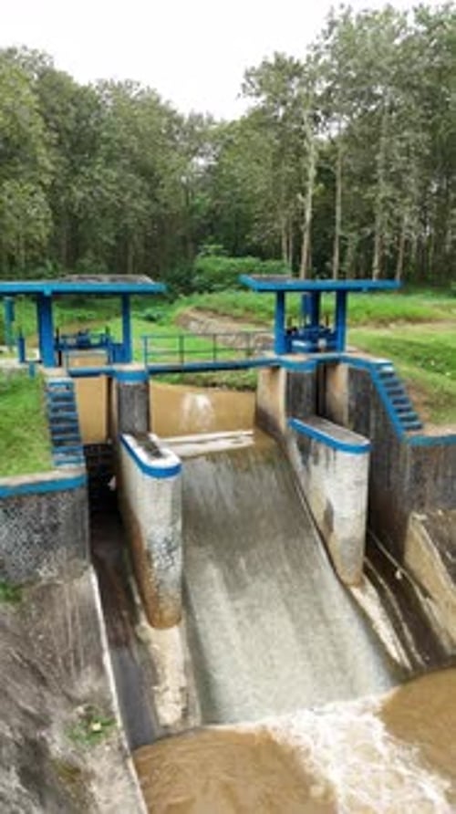 Drone view of small dam with brown water on forest