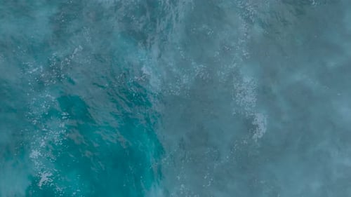Top Down Slow Motion Drone View of crystal clear water and crashing waves over shallow coral reef in