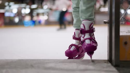 Child in Ice Skates Steps Onto Ice Rink