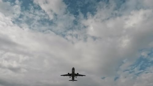 Airplane Flying Overhead in Cloudy Blue Sky