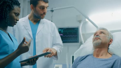 In the Hospital, Senior Man Lying in the Bed, Talks with Doctor and Nurse who Diagnose Him Using Ta
