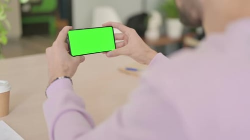 Rear View of Man Holding Smartphone with Green Screen