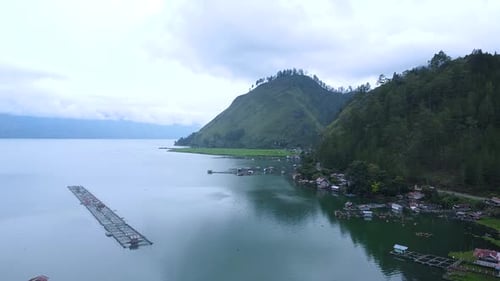 Des arbres et des maisons communautaires entourent le village de pêcheurs au bord du lac.