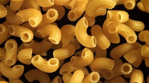Elbow Macaroni Pasta Floating on Black Background