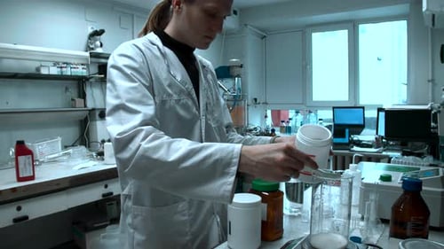 Un scientifique dévoué combine méticuleusement les poudres dans un contenant pour assurer une distribution uniforme pour