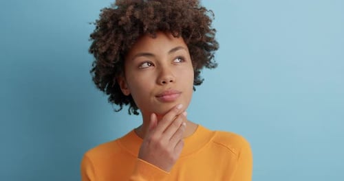 Contemplative Woman Thinking, Looking Up on Blue Background