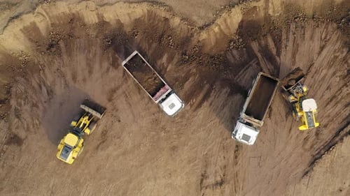 Excavators loading soil onto Trucks, Aerial view.