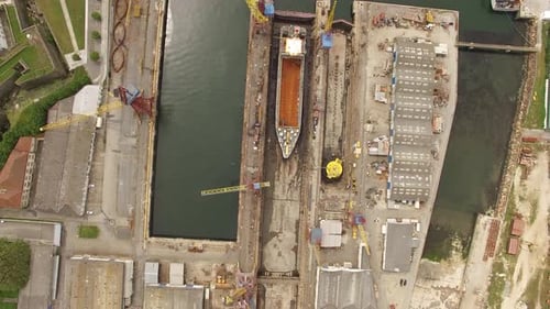 Immense cale sèche d'un chantier naval industriel surplombant les eaux calmes du port côtier
